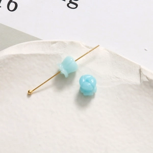 Detail von 6 mm hellblauen Maiglöckchen-Harzanhängern an goldenen Metallnadeln für DIY-Schmuck