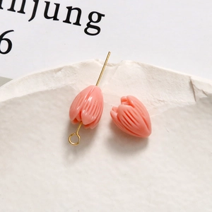 Detailed macro of pink tulip-shaped resin jewelry charms with gold metal attachment hooks