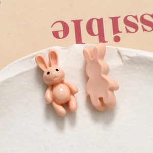 Macro view of 3D pink resin rabbit charms showing front and back texture details
