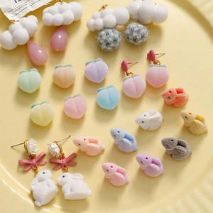 Flat lay of flocked macaron rabbit and peach charms for DIY jewelry making