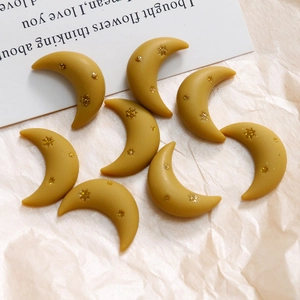 Macro detail of yellow resin crescent moon charms with gold star glitter for DIY crafts