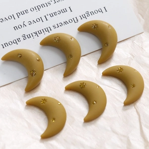 Detailed view of matte yellow crescent moon resin charms with gold glitter star details