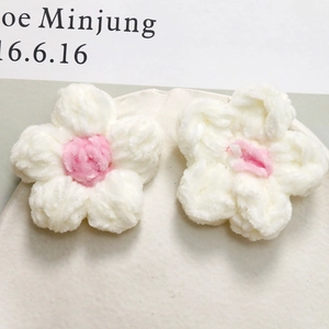 Dettaglio di fiori all'uncinetto fatti a mano in filato di velluto bianco e rosa per fai-da-te