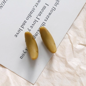 Detail of matte mustard yellow resin crescent earrings with subtle gold glitter accents