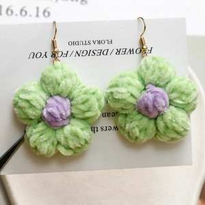 Vista macro dettagliata degli orecchini a fiore di peluche viola e verdi con ganci dorati