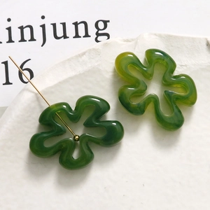 Détails macro de boucles d'oreilles fleurs en résine verte avec texture marbrée et clous dorés