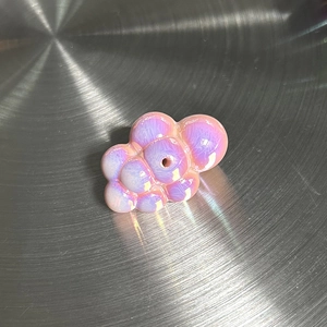 Détail macro d'une breloque nuage vintage avec une finition nacrée violette irisante