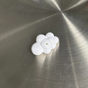 Macro shot of cloud-shaped white acrylic pendant bead with smooth glossy finish and center hole