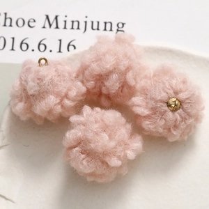 Macro view of light pink plush pom-poms with golden rings for DIY jewelry making