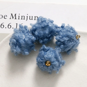 Macro view of light blue fuzzy lamb wool pom pom charms with gold metal loops