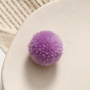 Macro-opname van een paarse pluizige garen pom-pom voor DIY knutselen op een keramisch bord