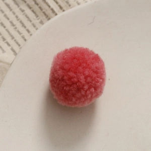 Gedetailleerd zicht op een zachte roze pompon op een wit bord voor DIY-knutselprojecten
