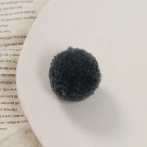 Gedetailleerd zicht op een donkergrijze pluizige pompon voor DIY-handwerk