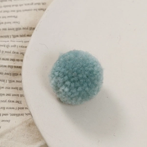 Detailopname van een zachte Morandi blauwe garen pompon voor DIY-sieraden
