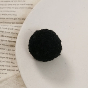 Macro-opname van een 3cm zwarte pluche pompon op een vintage boek voor DIY-projecten