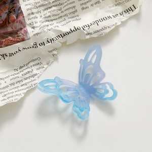 Macro shot of a hollow 3D butterfly hair clip with blue-purple gradient and glitter finish