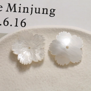 Macro detail of white acetate flower pendants with shell texture and central hole