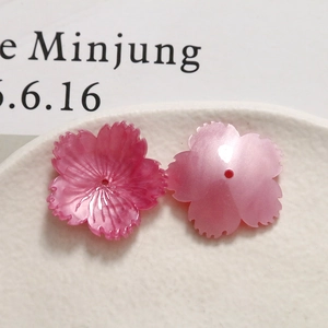 Close-up of pink pearlescent acetate flower beads with realistic petal texture and holes