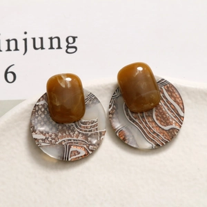Retro round acetate earrings with brown textured patterns on a ceramic plate