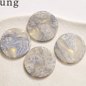 Macro view of four round acetate resin charms with blue marble texture for DIY jewelry