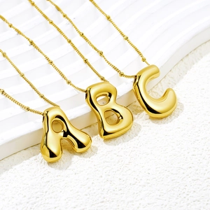 Macro detail of polished 18K gold plated balloon bubble A B C letter necklaces