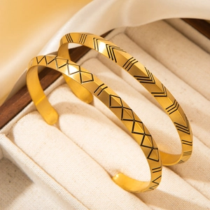 Detail of matte gold Viking rune bangles with black geometric triangular engravings