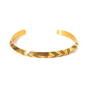 Detail of Nordic Viking runes and black V-shape arrow patterns on gold cuff bracelet
