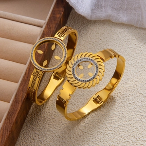 Detailed view of gold bangles featuring Greek meander patterns and pavé rhinestones