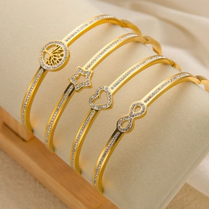 Detail van vier vergulde roestvrijstalen armbanden met fonkelende kristallen en bedels