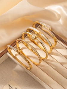 Close-up of gold stainless steel bangle set featuring shell inlay and rhinestone details
