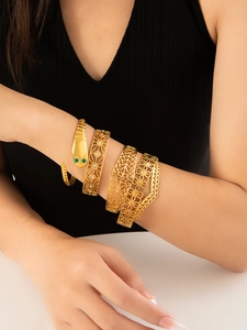 Dettaglio di quattro bracciali dorati con testa di serpente e motivi floreali pizzo