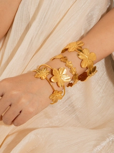 Dettaglio di bracciali dorati a fiori con finitura in metallo spazzolato elegante