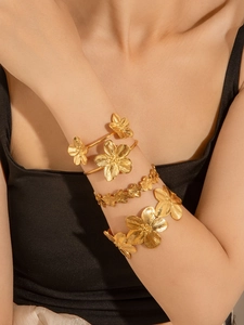 Dettaglio di quattro bracciali in acciaio dorato con motivi floreali e texture