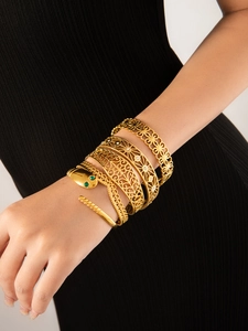 Primo piano di bracciali aperti dorati a forma di C con motivo a serpente e floreale