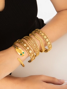 Dettaglio di un bracciale rigido a serpente dorato e set di bracciali con incisioni