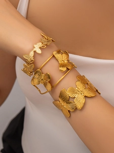 Dettaglio del set di tre bracciali a polsino dorati con farfalle sul polso