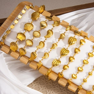 Detailansicht goldener Armbänder mit Muschel-, Herz- und Blattanhängern auf Display