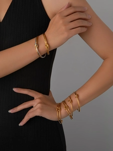 Dettaglio di eleganti bracciali a nodo dorati al polso con finitura metallica lucida