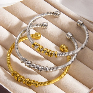 Detail of twisted cable bangles in gold and silver steel on beige velvet jewelry box