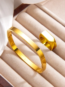 Close-up of polished 18k gold plated stainless steel square ring and bracelet set in a gift box