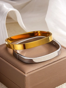 Detail showing polished gold and silver square bangles on leather box with silk backdrop