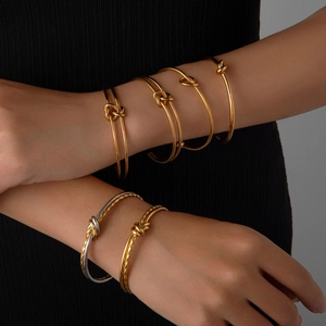 Anelli a nodo impilabili in finitura oro e argento su mani di modella con fondo nero
