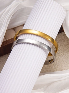 Macro view of minimalist polished 18k gold and silver bangles with hidden hinge detail