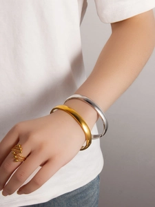 Detail showing minimalist gold and silver bangles with a spiral beaded ring on a model