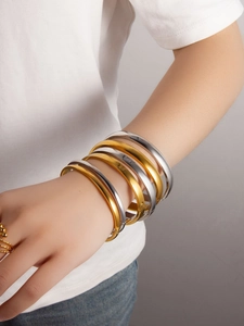 Close-up of minimalist gold and silver polished bangle stack on a model wrist