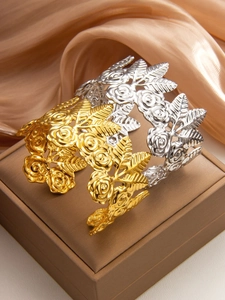 Close-up of gold and silver rose hollow bangles displayed on a luxury jewelry box