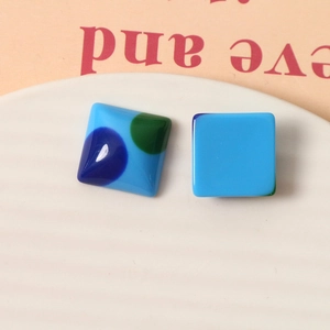 Macro view of blue retro polka dot square resin studs on a stylized display card