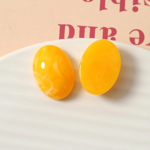Vue détaillée de breloques ovales en résine jaune avec texture marbrée sur plateau