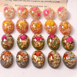 Makroaufnahme von 20 Vintage Harz-Cabochons mit Trockenblumen und Goldfolien-Akzenten