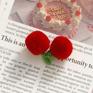 Detailed view of handmade knitted red cherries with green leaves for DIY craft accessories
